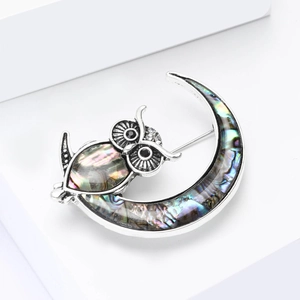 Vintage owl moon brooch with colorful abalone shell inlay on minimalist white background