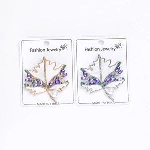 Detail of maple leaf brooch with purple crystals and pearl on jewelry display card