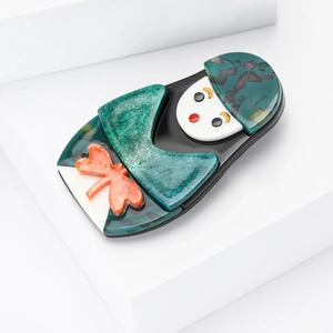 Détail de la broche Matriochka en acrylique vert avec paillettes dorées et textures 3D