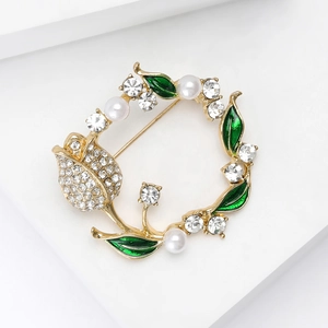 Macro shot of gold tulip wreath brooch with green enamel leaves and sparkling crystals