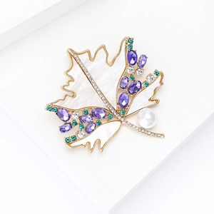 Macro detail of maple leaf brooch with white shell, sparkling zircon, and purple gems