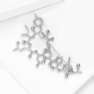 Macro shot of silver chemical molecular formula brooch with smooth metal texture finish