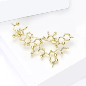 Detail of gold chemical formula brooch with oxytocin molecular structure and pin clasp