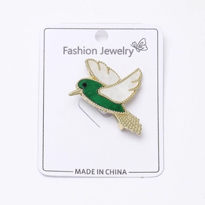 Détail d'une broche colibri avec corps en émail vert et ailes en nacre synthétique