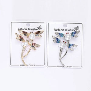 Détail de broches libellules avec ailes émaillées et perles sur carte bijoux