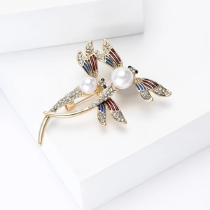 Détail d'une broche libellule avec émail rouge et bleu et perles blanches