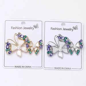 Detail view of gold and silver butterfly brooches with purple crystals and pearls