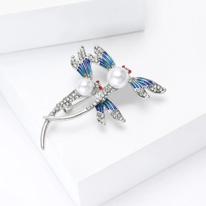 Détail de broche libellule avec ailes en émail bleu, strass scintillants et perles blanches