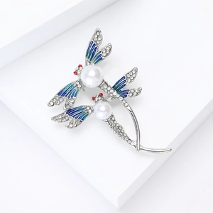 Détail de la broche libellule avec émail dégradé bleu et perles blanches élégantes