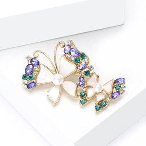 Elegant gold butterfly brooch with purple crystals and white pearls on white stand