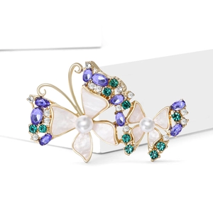 Elegant gold butterfly brooch with purple crystals and pearls on white background