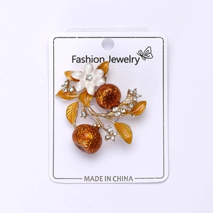 Macro shot of retro persimmon brooch with enamel white flower and rhinestones on gold stem