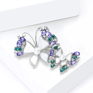 Detailed close-up of butterfly brooches with purple crystals, enamel wings, and pearls