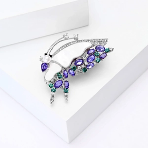 Broche papillon exquise avec cristaux violets et nacre sur un support blanc élégant