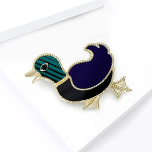 Elegant gold-tone duck brooch with colorful enamel patterns on white geometric stands