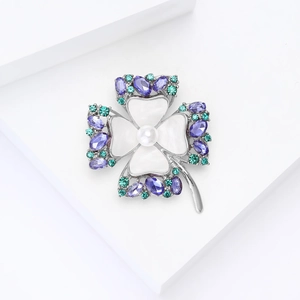 Detalle del broche de trébol con esmalte blanco, perla y cristales púrpuras en base de plata