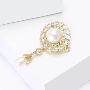 Detail view of flower brooch with golden frame, white pearls and sparkling crystals