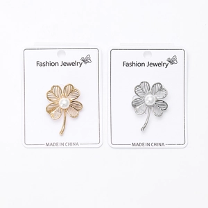 Detail of clover brooches in gold and silver finish with elegant pearl center and hollow petals