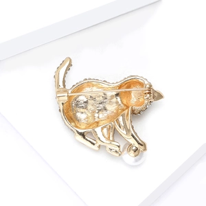 Broche chat dorée élégante avec strass et perle blanche sur des blocs blancs