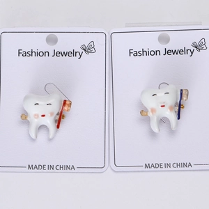 Close-up of creative tooth pins with toothbrushes on white fashion jewelry card