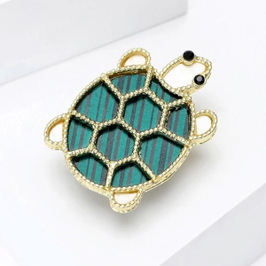 Close-up of elegant turtle brooch with green enamel shell and gold-tone beadwork textures