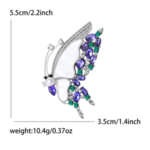 Broche papillon élégante en nacre naturelle sertie de pierres violettes et perle blanche