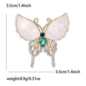 Elegant butterfly brooch with shell wings, green gems and crystals on a white background