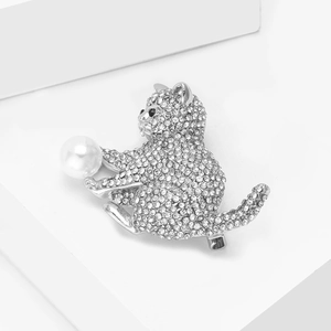 Macro détaillée d'une broche chat argentée avec des strass et une perle blanche nacrée