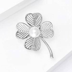 Macro shot of silver-toned hollow clover brooch with central pearl inlay detail