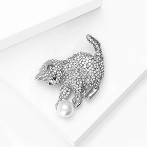 Gros plan détaillé d'une broche chat argentée avec strass brillants et perle blanche