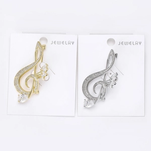 Detailed view of musical note brooches in gold and silver with zircon stones