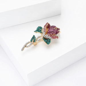 Vue détaillée d'une broche rose élégante avec strass roses et violets et feuilles vertes