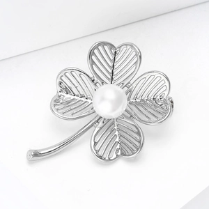 Macro shot of silver hollow clover brooch with a central large white pearl detail