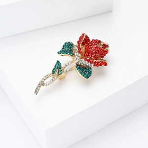 Détail d'une broche rose rouge élégante avec strass et feuilles sur socle blanc