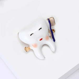 Detailed macro shot of creative cartoon tooth brooch with white enamel finish and gold edges