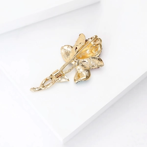 Vue arrière détaillée d'une broche rose dorée avec épingle de sûreté et texture mate