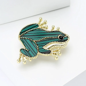 Macro detail of frog brooch with green striped enamel and golden beaded edges
