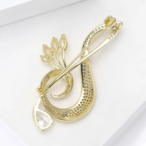Close-up of golden musical note brooch with zircon inlay on a white platform