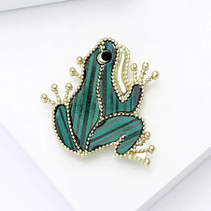 Cute green striped frog brooch in gold-plated frame with black bead eyes on white background