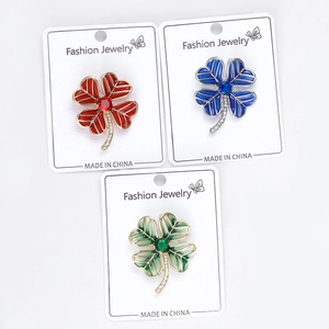 Close-up of three colorful clover brooches in red, blue and green with enamel finish