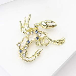 Squisita spilla a forma di scorpione dorato con smalto bianco e strass blu scintillanti
