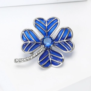 Macro detail of silver four-leaf clover brooch with deep blue enamel and gems
