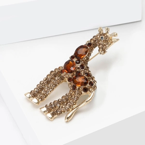 Dettaglio macro di spilla a giraffa dorata con strass champagne e cristalli ambrati