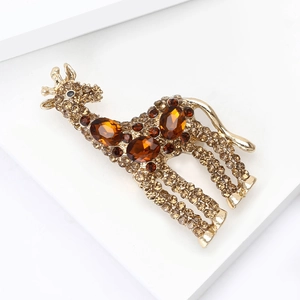 Dettaglio spilla a forma di giraffa dorata con strass color ambra e champagne di lusso