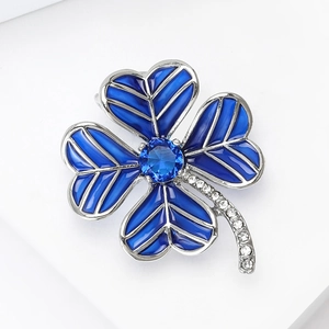 Detailed view of silver four-leaf clover brooch with blue enamel and crystal inlay
