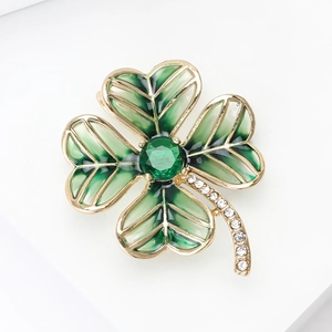Detailed macro view of four-leaf clover brooch with green enamel and crystal accents