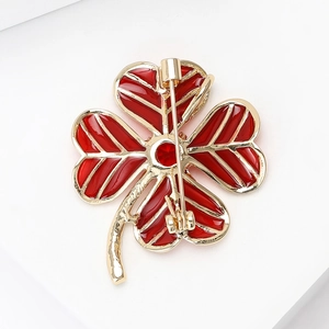 Detail of the golden clover brooch back showing the red enamel finish and pin fastener