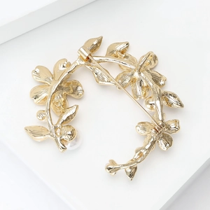 Detaillierte Ansicht der goldenen Blumenkranz-Brosche mit Perlen und klassischem Nadelverschluss