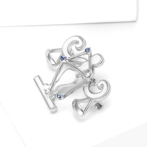 Broche vélo en argent sertie de strass bleus et blancs sur un fond blanc épuré