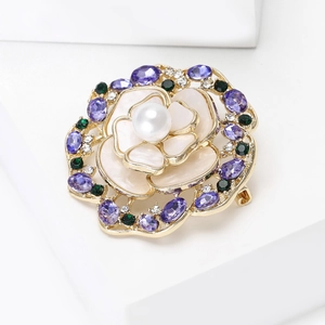 Détail d'une broche fleurie violette avec perle d'eau douce sur monture dorée chic